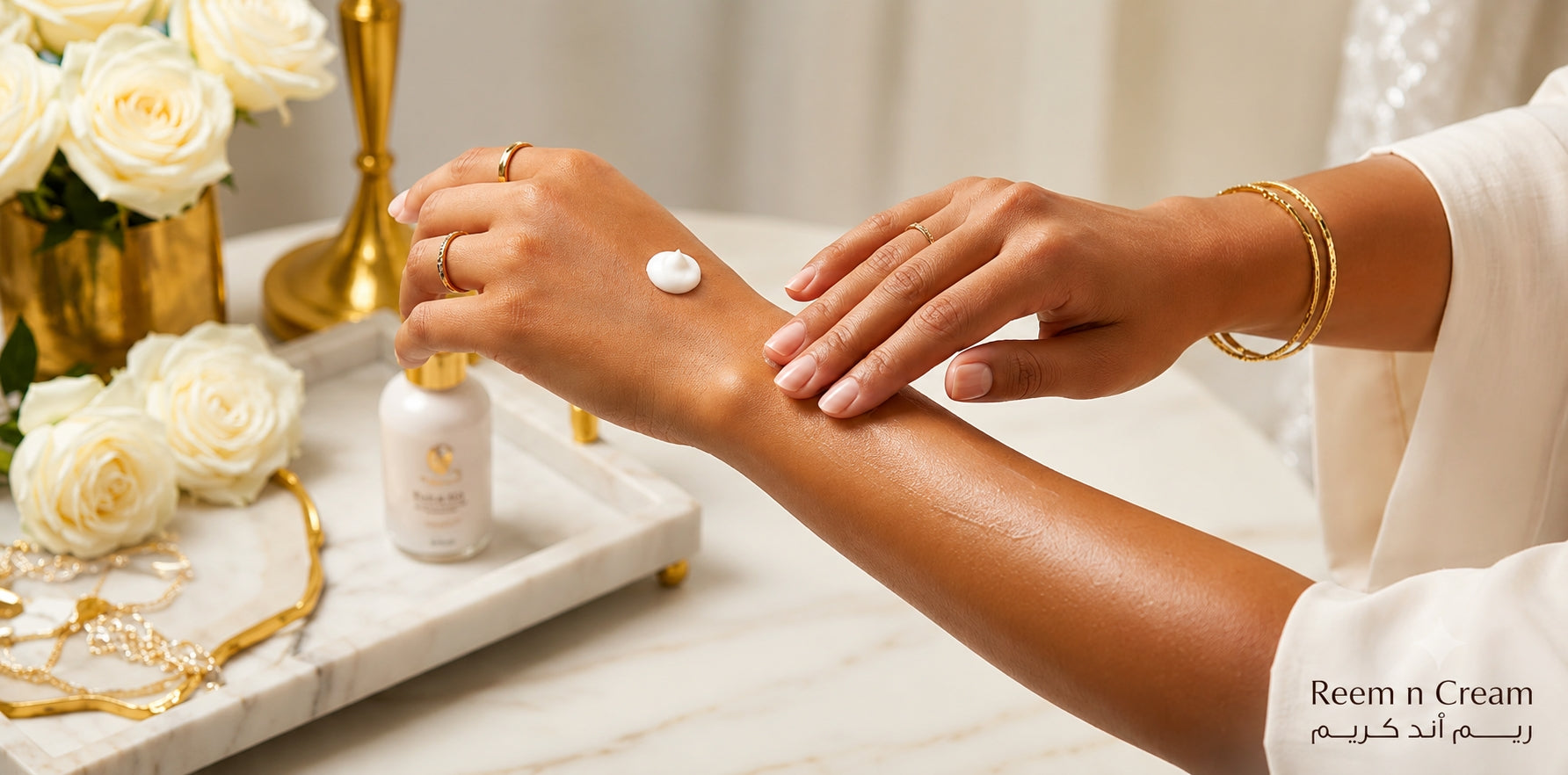 **Alt text (125 characters):**  Woman applying moisturizing body lotion to her arm on a marble vanity with white roses, luxury skincare and elegant gold accents.