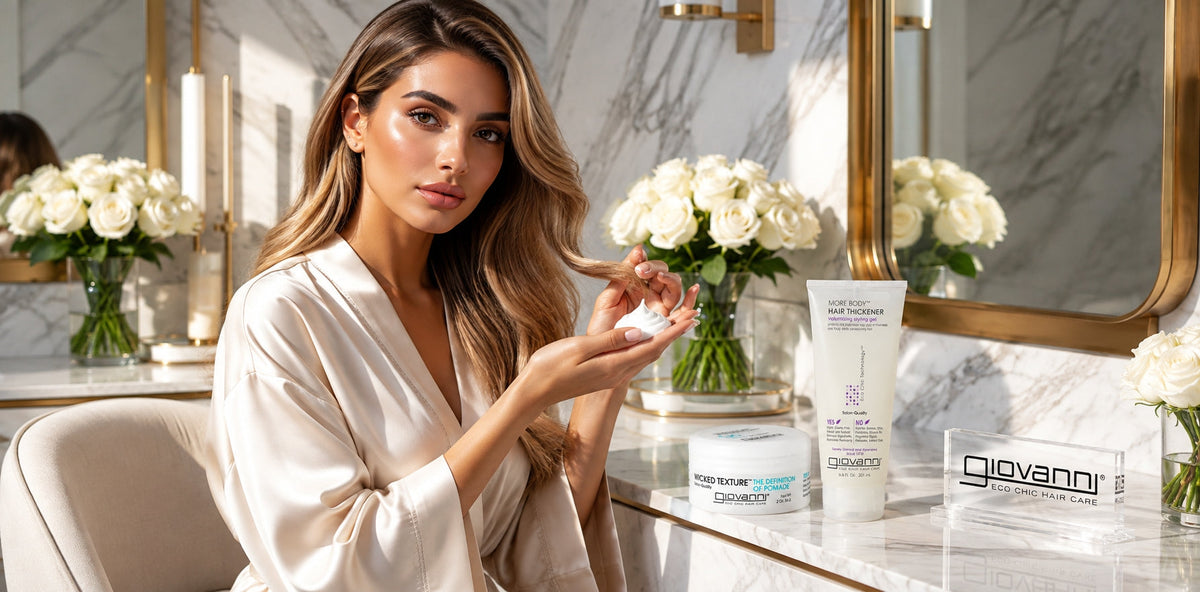 Giovanni hair thickener and styling pomade products displayed on a luxury vanity with a woman holding hair cream.