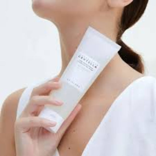 Woman in white outfit holding SKIN1004 Centella Cleansing Gel Foam tube near her neck and chin area.
