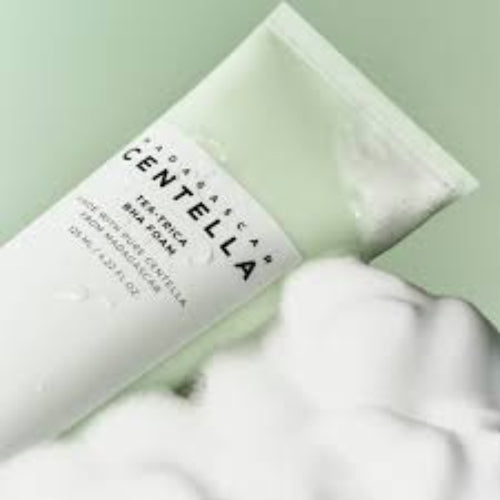 Close-up of Madagascar Centella Tea-Trica BHA Foam cleanser tube resting beside rich foam, highlighting creamy texture and soothing skincare.