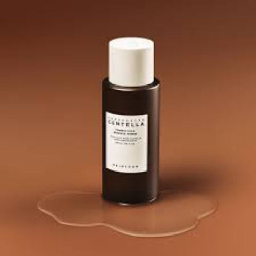 SKIN1004 Madagascar Centella Probio-Cica Essence Toner bottle with clear liquid texture on brown background.
