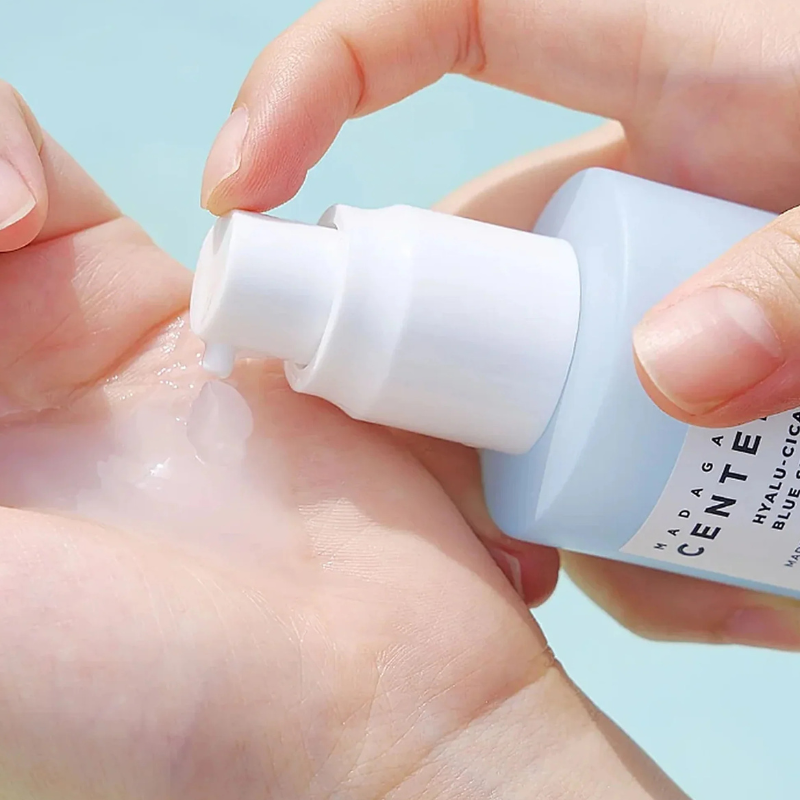 Hand applying skincare product from a bottle labeled 'Cetaphil' against a light blue background. Skin1004 Hyalu Cica Blue Serum close-up showing lightweight, fast-absorbing texture in KSA